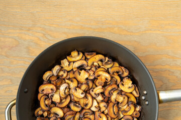 Pan-fried Champignon mushrooms on a frying pan. Brown edible fungi slices prepared.