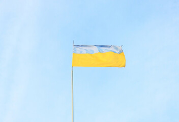 Ukrainian blue and yellow flag in the wind. Background of blue sky and white clouds. The national flag of Ukraine.