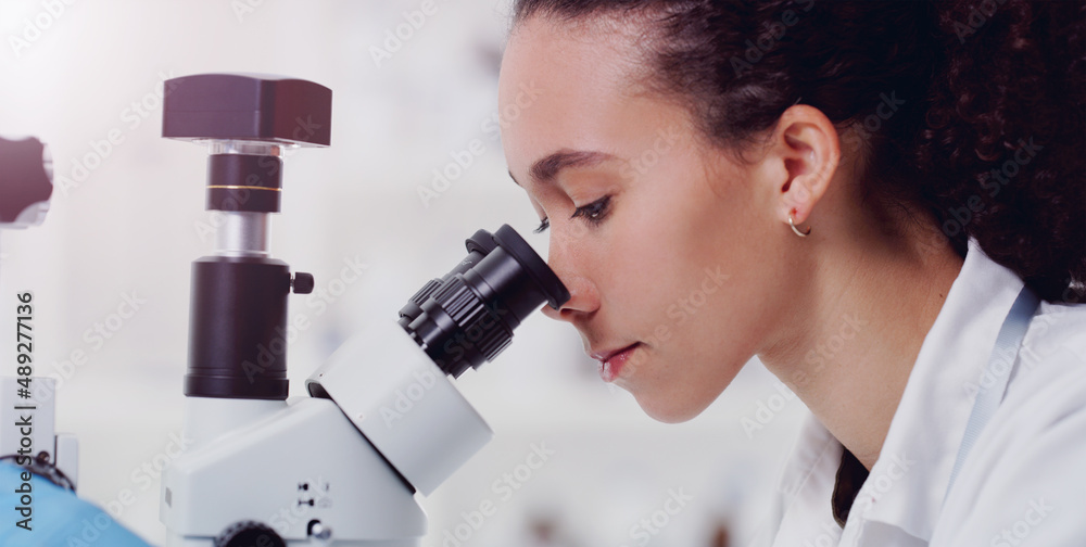 Wall mural stay curious about the world. shot of a young scientist using a microscope in a lab.