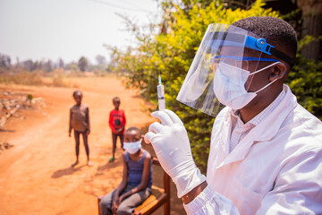 An African doctor is about to vaccinate children to prevent coronavirus infection. Vaccination...