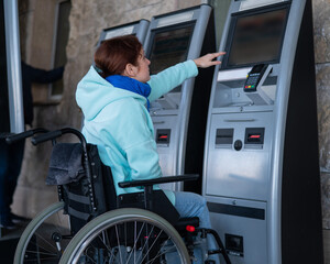 A Caucasian woman in a wheelchair does not reach the self-service checkout at the railway station....
