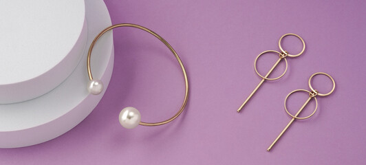 Panoramic shot of modern golden bracelet with pearls and geometric design earrings pair on white...