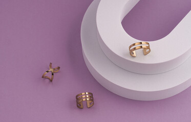 Top view of three modern rings on white podium on violet background with copy space