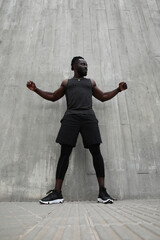 Black young man doing hard workout outdoors. Vertical photo.