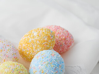Colorful eggs on white fabric background. Happy Easter concept.