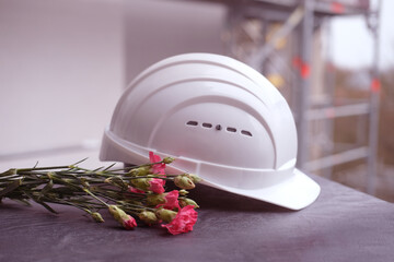 white hardhat, red carnations, helmet on background of buildings, protection inspecting at...