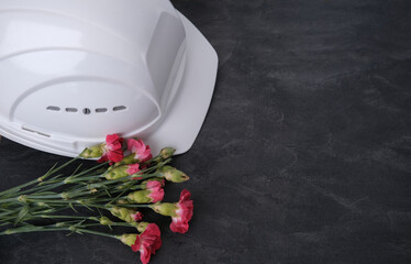 white hardhat, red carnations, helmet on background of buildings, protection inspecting at...