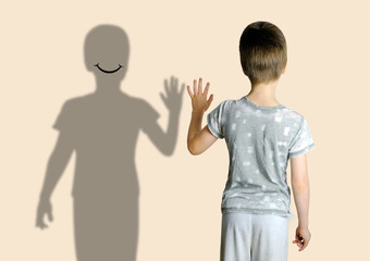 child 8-10 years old in gray t-shirt extended his hand to his shadow, concept imaginary friend,...