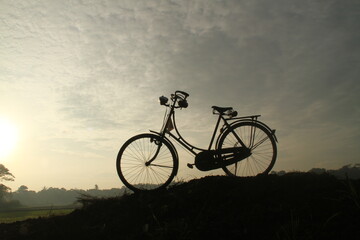 Fototapeta na wymiar silhouette of an old bicycle by the rice field, indonesia 