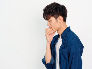 Portrait of handsome Chinese young man with curly black hair in blue shirt posing against white...