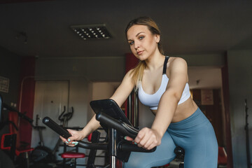 Fototapeta na wymiar one woman young adult female training at the gym in day sitting riding on the spinning bike bicycle cardio workout exercise real people copy space