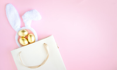 Gift bag with rabbit ears and golden Easter eggs.