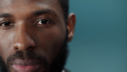 Fototapeta premium A young black bearded man in a official suit blinks and looks at the camera