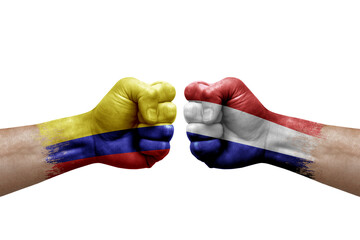 Two hands punch to each others on white background. Country flags painted fists, conflict crisis concept between colombia and netherlands