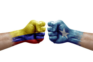 Two hands punch to each others on white background. Country flags painted fists, conflict crisis concept between colombia and somalia