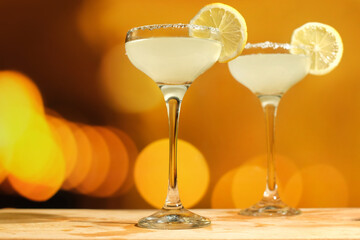 Two drinking glasses of Margarita cocktails with lemon and salt. Alcoholic cocktails on festive golden background.