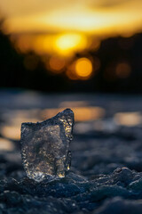 Transparent piece of ice on the blurred background of the sunset