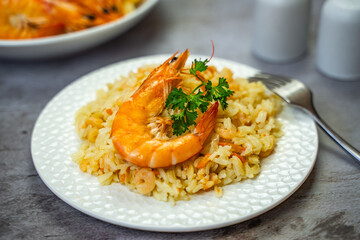 Rice with shrimps on a white plate on the table.