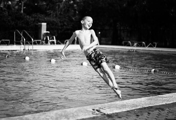 Boy jumping into the pool in black and white