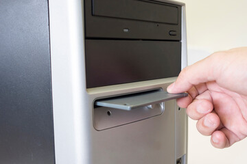 hand inserts  floppy disk into a  computer
