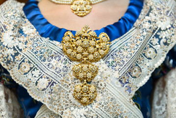 Traditional style gold jewelery on the chest of a woman with traditional fallas costume in Valencia.