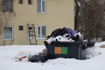 The garbage can on the street is full, there is a lot of garbage around, a garbage dump. Environmental pollution.