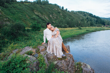 Romantic inloved couple sitting on rocks by the river.