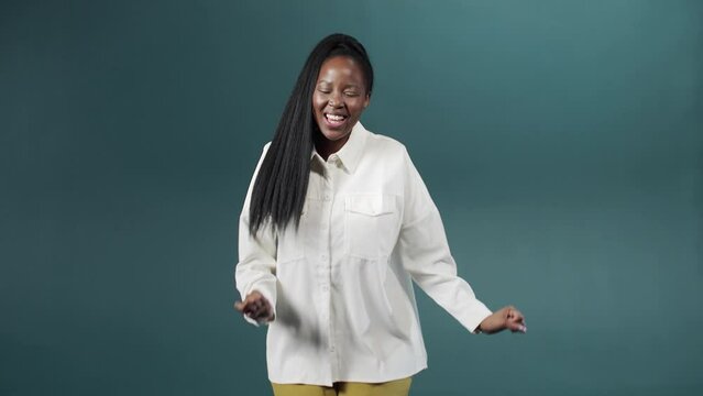 Beautiful black woman dancing with inspired face expression on green background