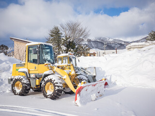 yellow snowplow vehicles and piled up snow beside them