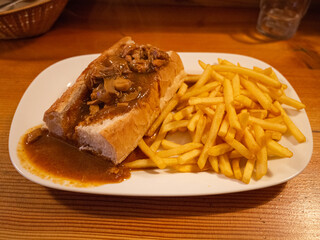 bread with gravy source and french fries on the white plate in the american restaurant
