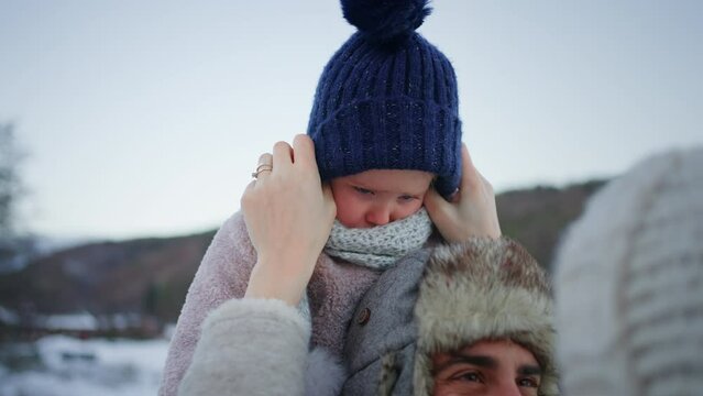 Happy young family on winter holiday with small child outdoors in snowy nature.