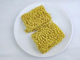 Dry yellow noodles on a white plate on a with background