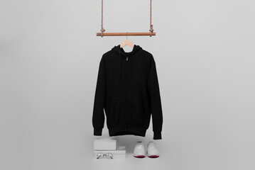 Black zip hoodie hanging on wood hanger isolated on plain background