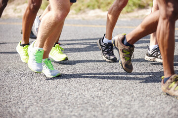 Who will be the winner. Shot of the legs of a group of men running a road race.