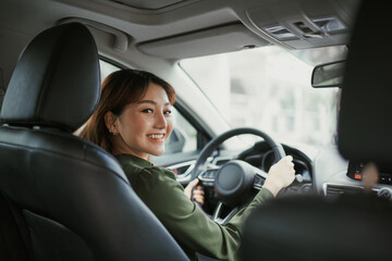 Fototapeta na wymiar Asian women driving a car and smile happily with glad positive expression during the drive to travel journey