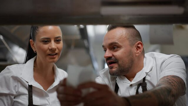 Chef And Cook Taking Order Slip In Commercial Kitchen.