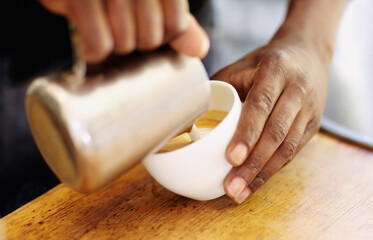 Topping off your cappuccino. Cropped shot of a barista pouring milk froth into a cappuccino.