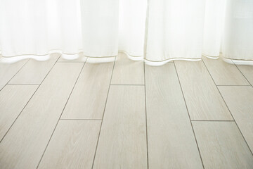 Bright white curtains hang on the imitation wood floor