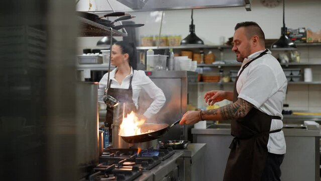 Professional chef preparing meal, flambing indoors in restaurant kitchen.
