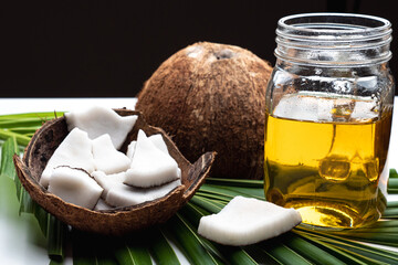 Coconut meat and coconut oil in glass bottle on coconut leaf.