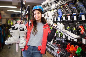 Glad girl in skiing outfit satisfied with choice in modern store of sports equipment