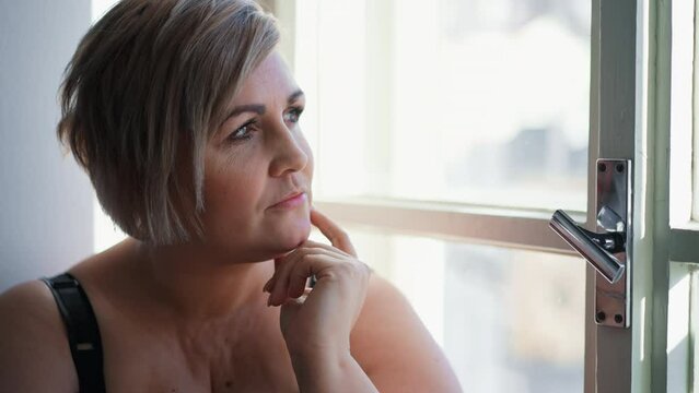 Depressed lonely fat woman sitting aby window at home and thinking.