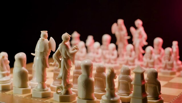 
A close up dolly shot tracking in over the pieces of a chessboard, the pawns in the front row resemble a wise old man and are lined up ready to begin a game of chess 