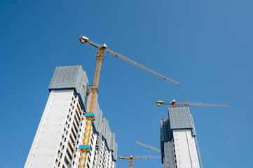 It's a fine day with blue sky, and the tower crane on the high-rise buildings in the city is under construction