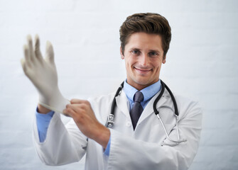 This wont take long..... Shot of a smiling doctor pulling on a surgical glove.