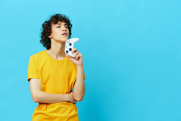 gamer plays with joystick in yellow t-shirts blue background