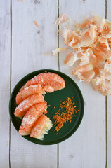 Peeled pink pomelo segments on a plate with chili powder