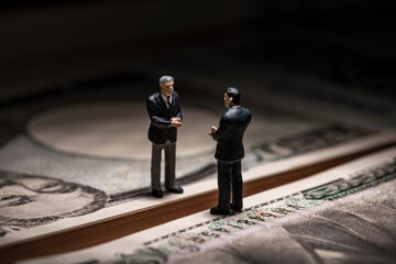 お金（札束）とミニチュアのビジネスマン