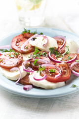 Summer Salad with Mozzarella Cheese, Tomatoes and fresh Basil. Bright wooden background. Close up. 