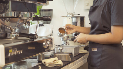 Close up of woman worker, barista in apron making a coffee by using coffee machine in kitchen bar of coffee shop. Business service. People lifestyle.
